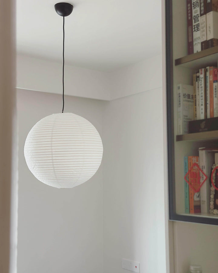 Small unlit rice paper pendant with a black wire beside a study bookcase