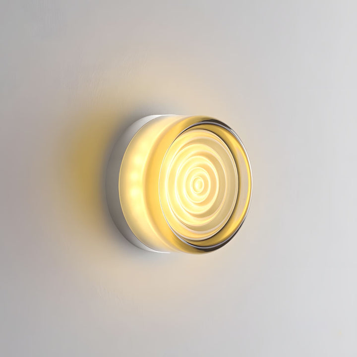 Smoke gray glass wall sconce with concentric rings and warm light.