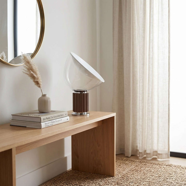 Coffee Taccia table lamp on a long wood console beside sheer curtains and a round wall mirror