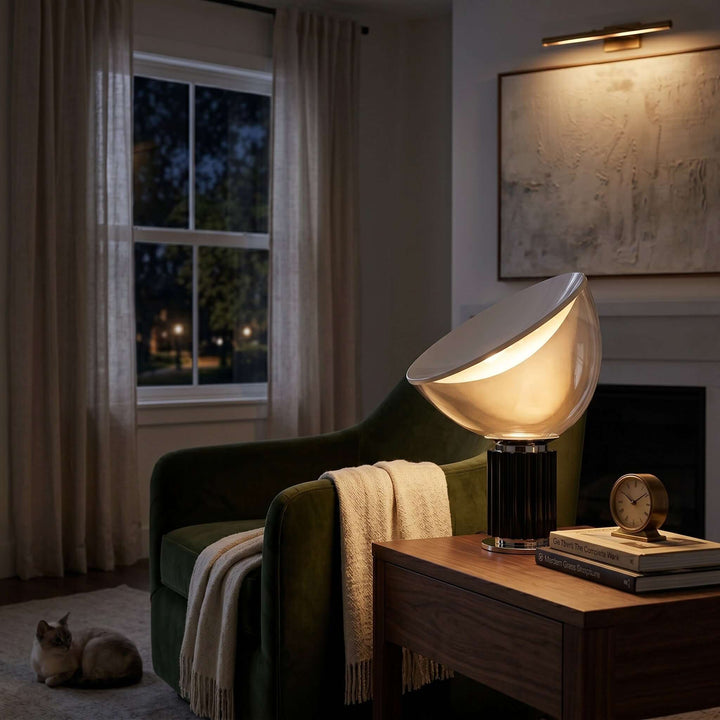 Glowing black Taccia table lamp beside a green lounge chair in a cozy evening reading room
