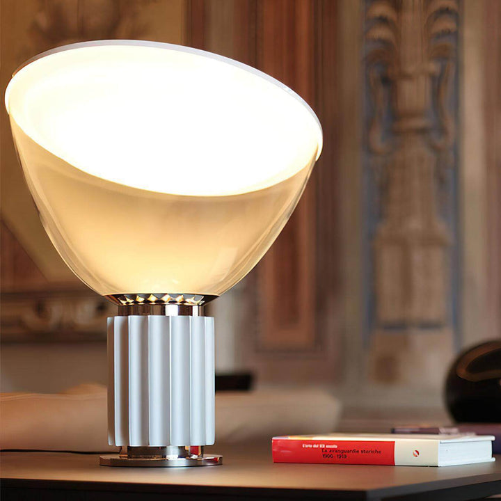 Close view of the illuminated Taccia glass table lamp with a silver fluted base and warm diffused light