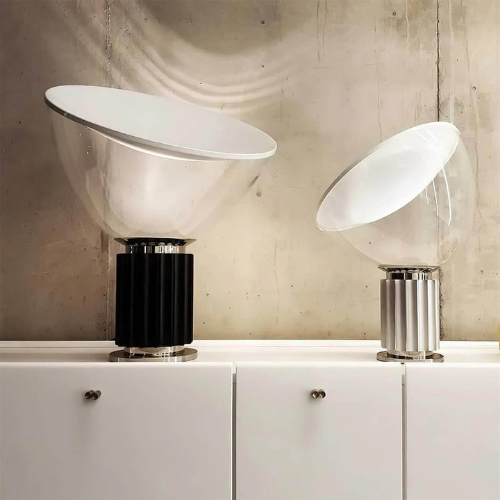Large black and small silver Taccia table lamps displayed together on white cabinets