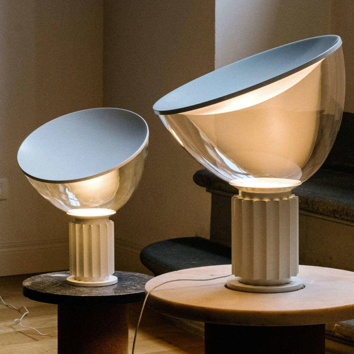 Two illuminated Taccia table lamps in different sizes with light silver fluted bases on round tables