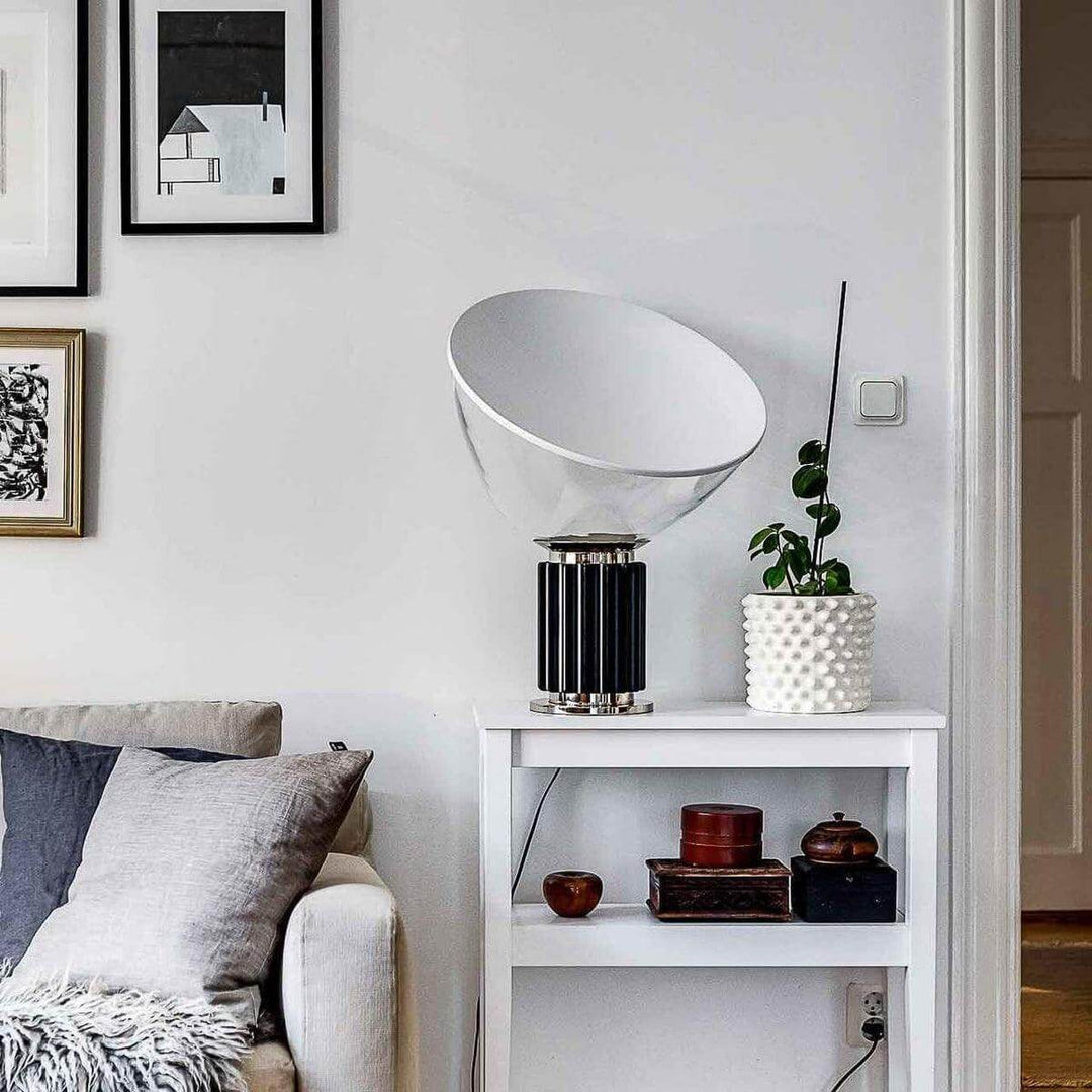Black Taccia table lamp on a white side table beside a sofa in a bright eclectic living room