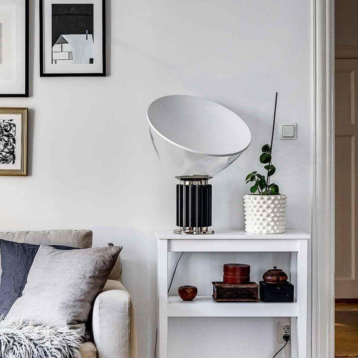 Black Taccia table lamp on a white side table beside a sofa in a bright eclectic living room