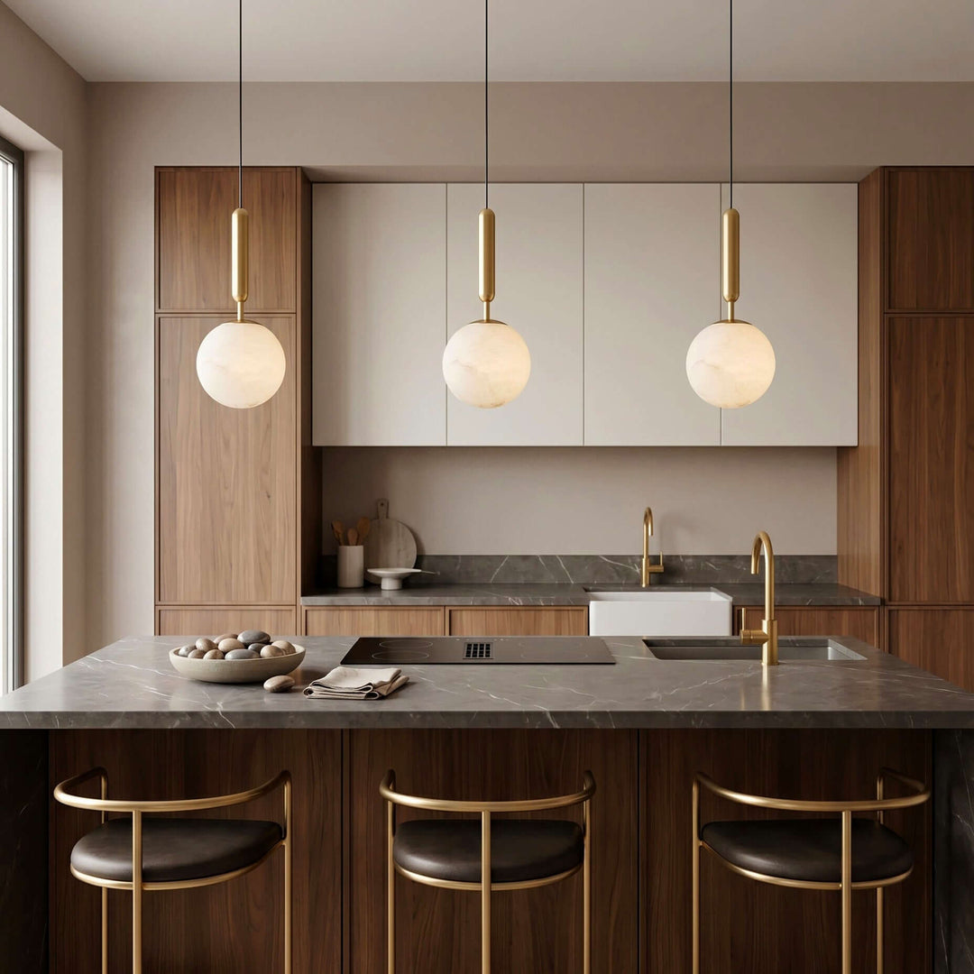 Three brass and alabaster pendant lights hanging above a dark wood kitchen island
