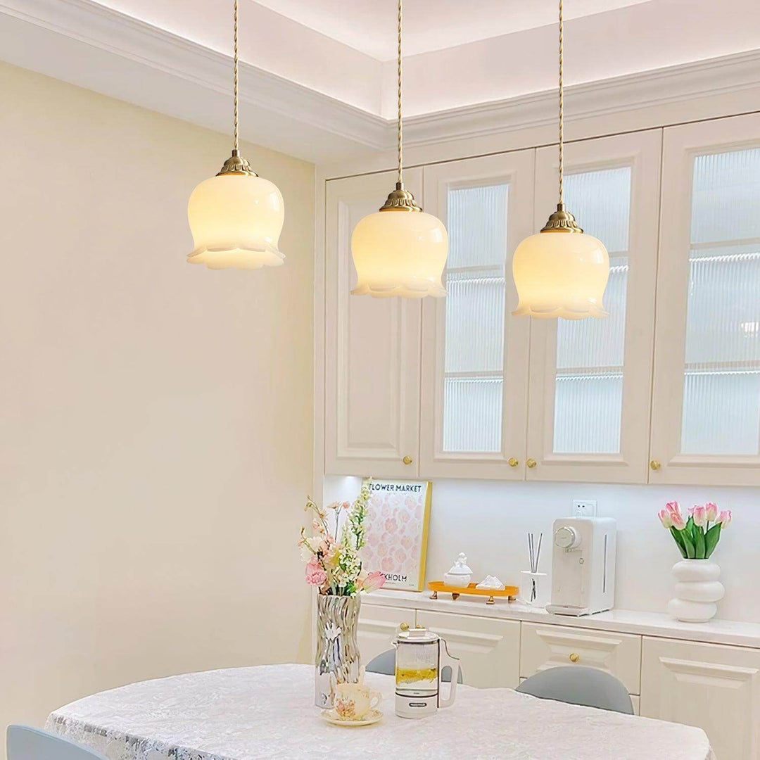 Three brass flower pendant lights hanging in a row above a dining table in a bright kitchen-dining space
