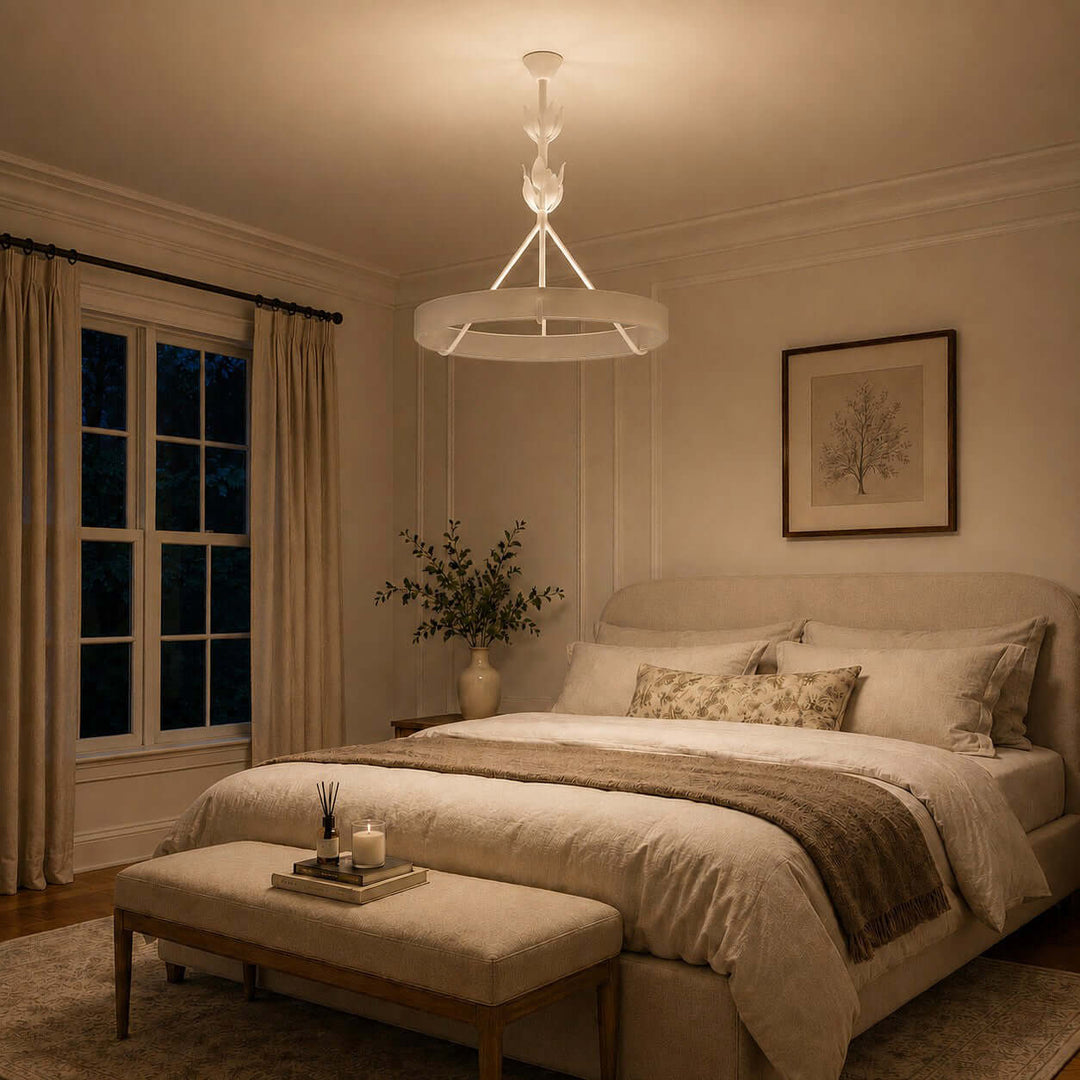 Warm white Tinsley bedroom chandelier above a neutral upholstered bed at night.