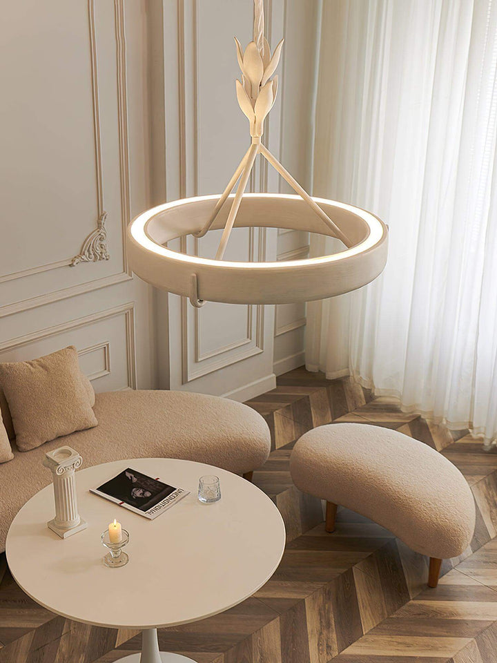 Illuminated Tinsley LED chandelier above a curved cream sofa and round table in a refined sitting area.