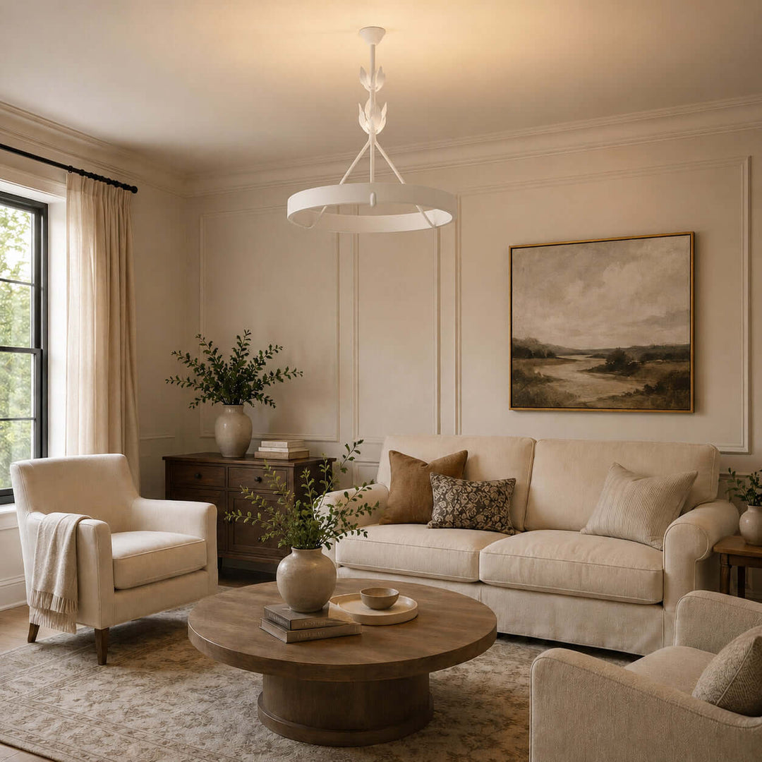 White Tinsley plaster chandelier above a cream sofa and round wood coffee table in a neutral living room.