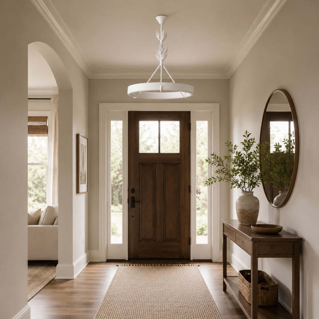 Tinsley plaster chandelier above a bright foyer with a wood front door and oval wall mirror.