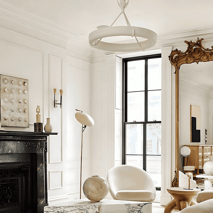 White Tinsley chandelier in an ornate living room with a black marble fireplace and carved gold mirror.