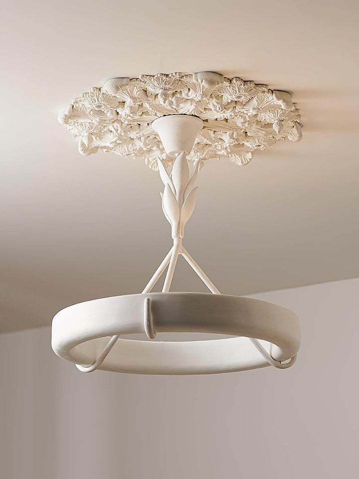 Front detail of the white Tinsley ring chandelier suspended from an ornate plaster ceiling medallion.