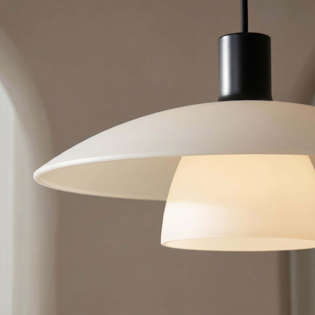 Close-up of the Verona pendant lamp with a white metal shade, black socket, and glowing glass diffuser
