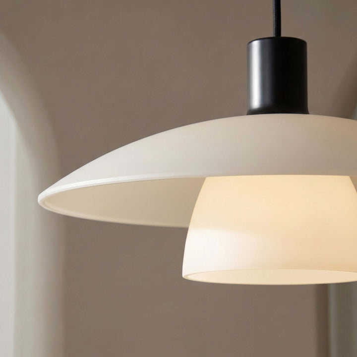 Close-up of the Verona pendant lamp with a white metal shade, black socket, and glowing glass diffuser