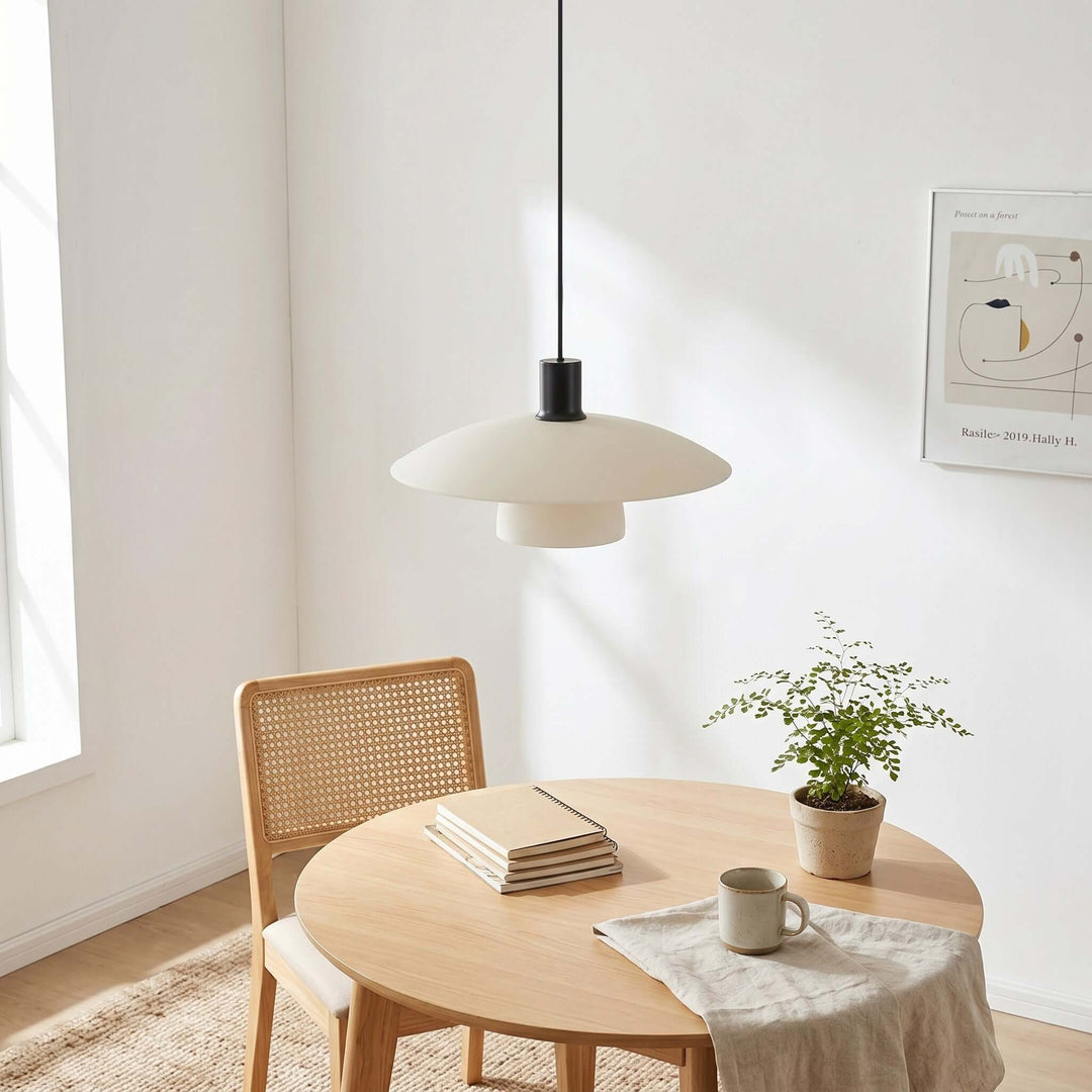 Unlit Verona pendant light above a round table styled with books, a mug, and a small plant
