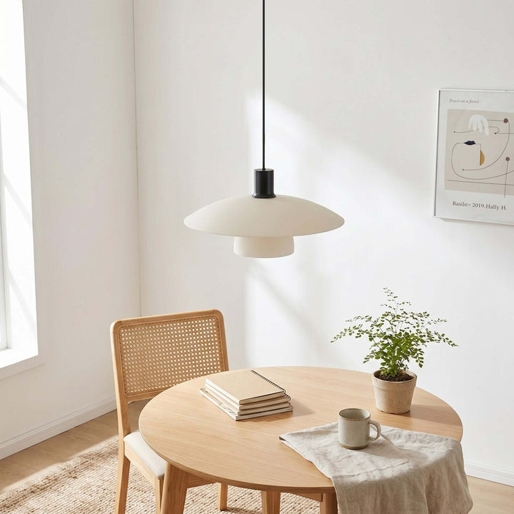 Unlit Verona pendant light above a round table styled with books, a mug, and a small plant