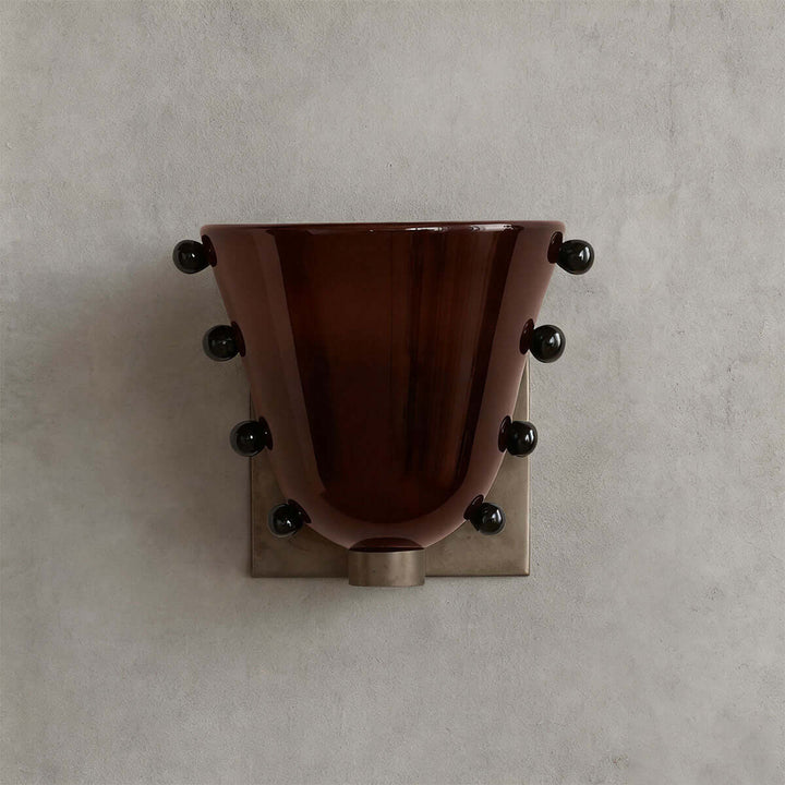Front view of a brown Vestra wall sconce with black sphere accents