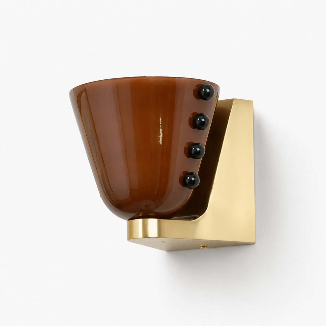 Brown Vestra glass wall sconce with a gold base and black sphere accents on white