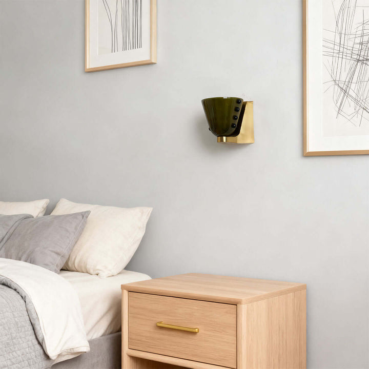 Green Vestra glass wall sconce mounted beside a bed in a modern neutral bedroom