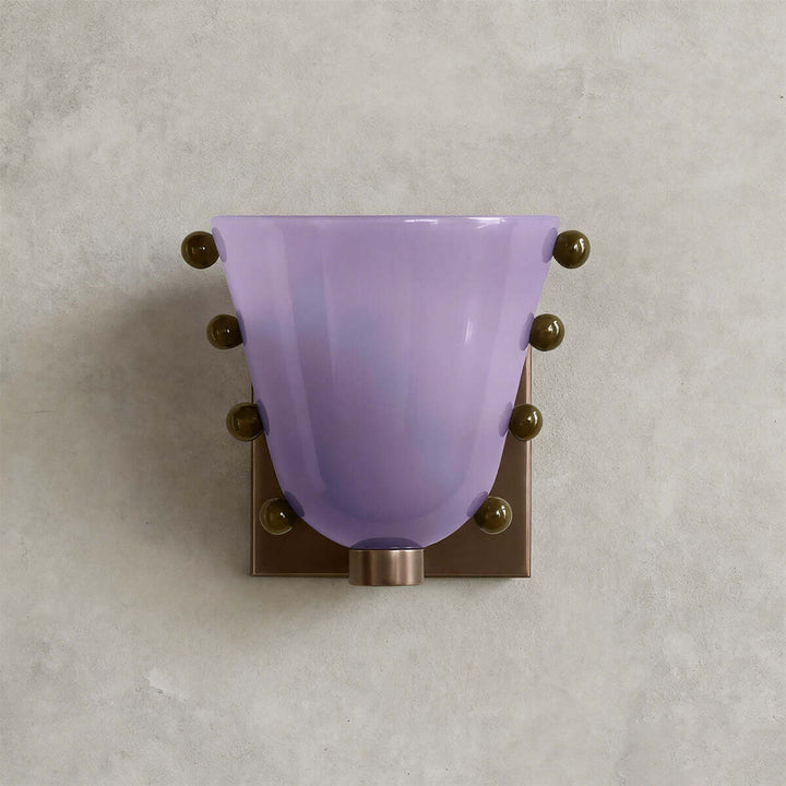 Front view of a purple Vestra glass wall sconce with a brass-toned backplate