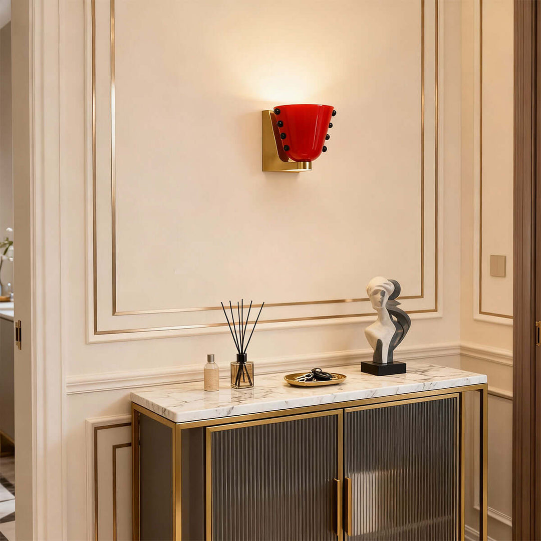 Red Vestra glass wall sconce above a fluted console in an elegant hallway