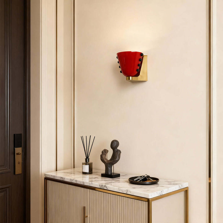 Red Vestra wall sconce illuminating an entryway above a marble-topped console