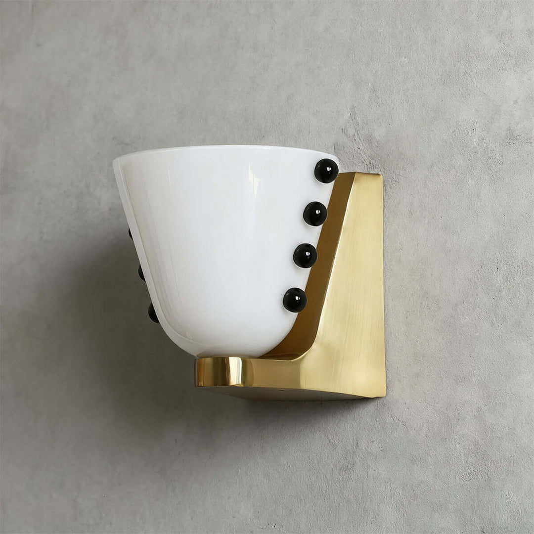 Side view of a white Vestra wall sconce with black sphere accents and a gold base