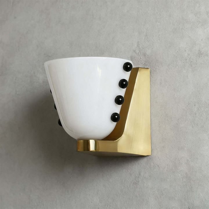 Side view of a white Vestra wall sconce with black sphere accents and a gold base