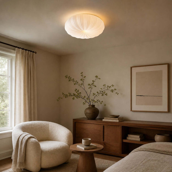 Warm white ceiling light above a bedroom side table and armchair.