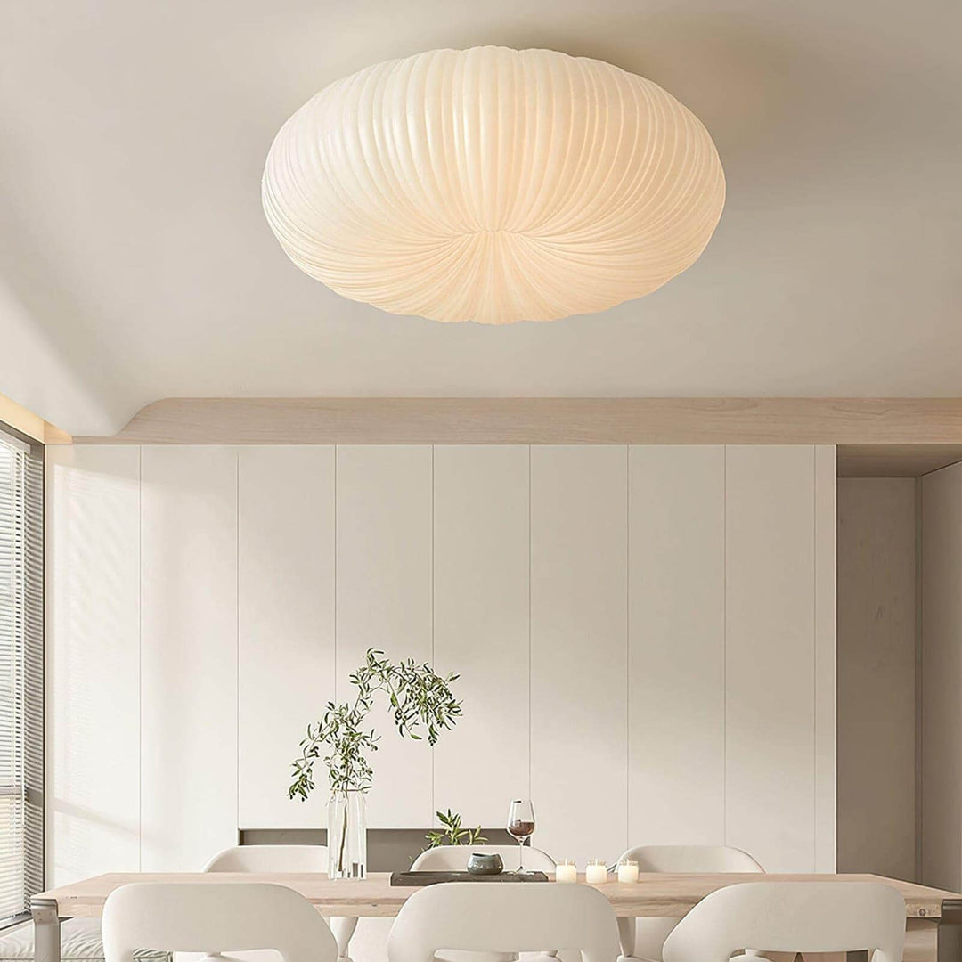 White round ceiling light above a dining table in a bright modern room.