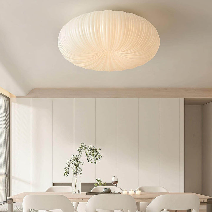 White round ceiling light above a dining table in a bright modern room.