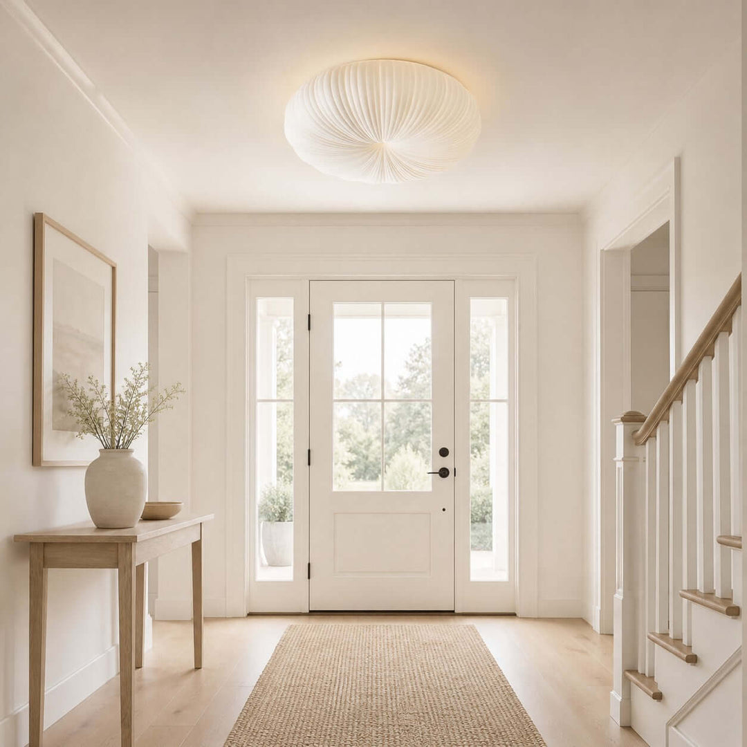 White round flush mount ceiling light in a bright entry hallway with stairs.