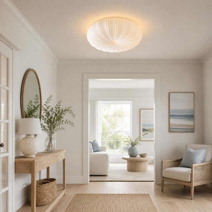 White flush mount ceiling light in a bright entry sitting area with mirror and chair.