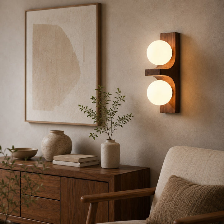 Double wall sconce above a sideboard with artwork and dining chair nearby.