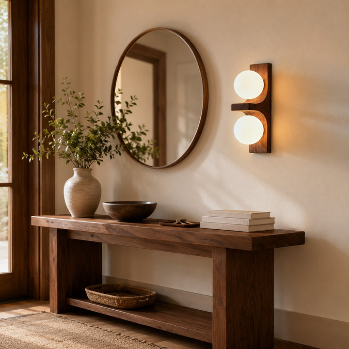 Wood double wall sconce beside a round mirror above an entry console table.