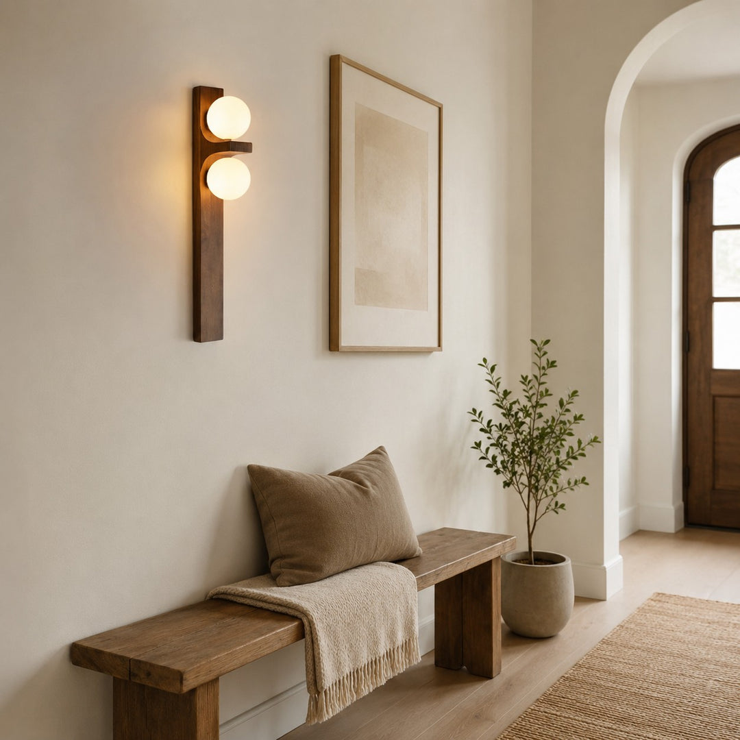 Double wall sconce lighting a hallway bench with framed wall art nearby.
