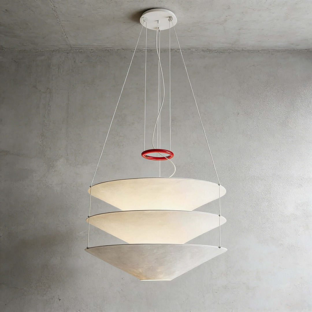 Floating pendant light with layered white shades shown against a concrete wall.