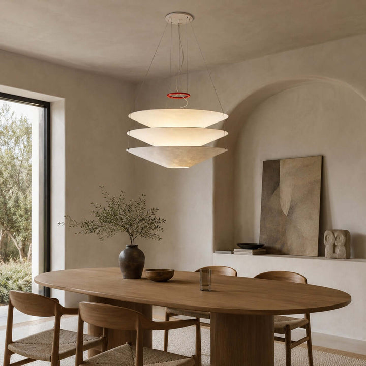 White layered pendant light above a wooden dining table near a window.