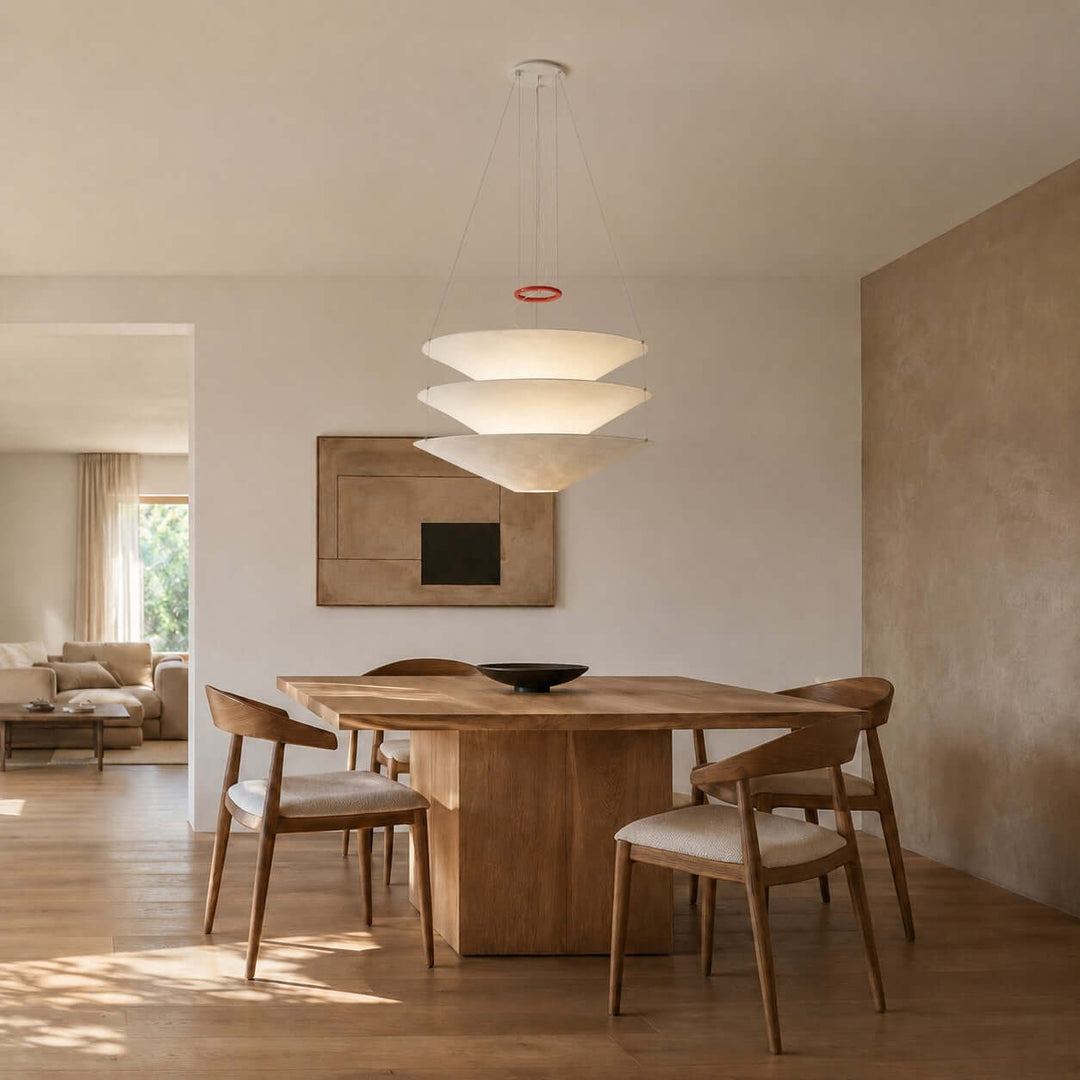 White floating pendant light hanging above a simple wooden dining table.