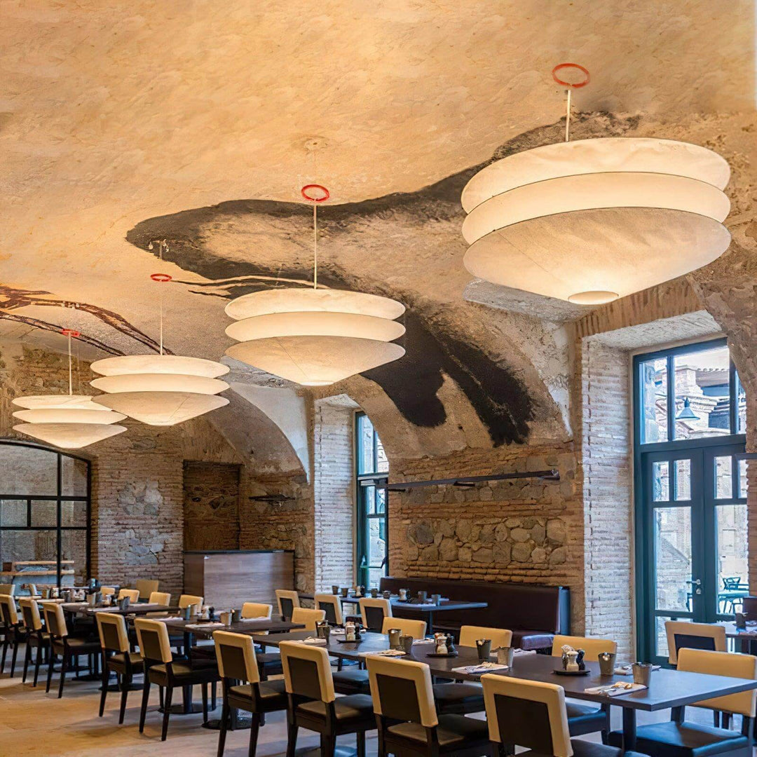 Multiple floating pendant lights above tables in a restaurant dining hall.