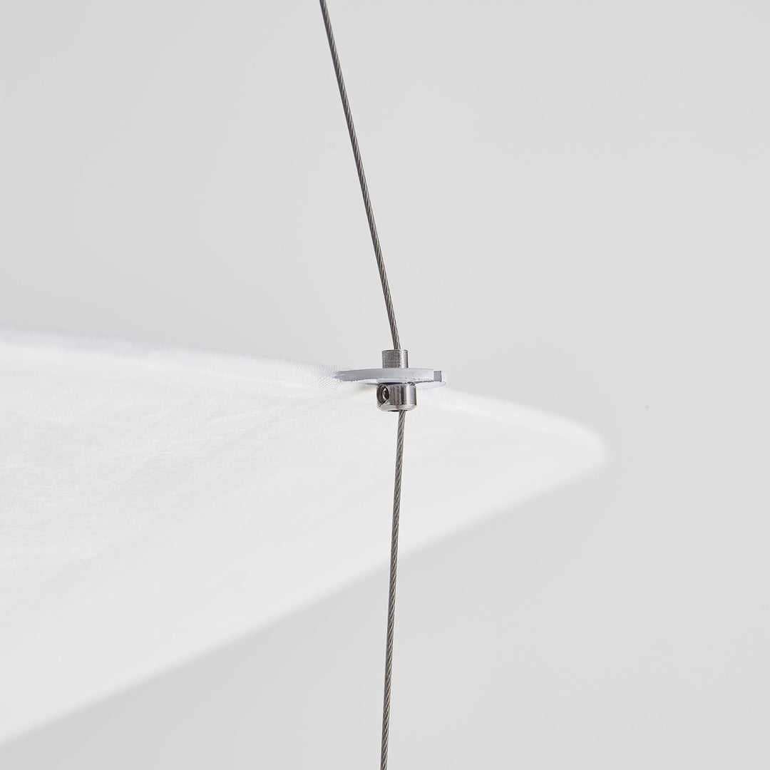 Close-up of a suspension wire attached to the edge of the layered shade.