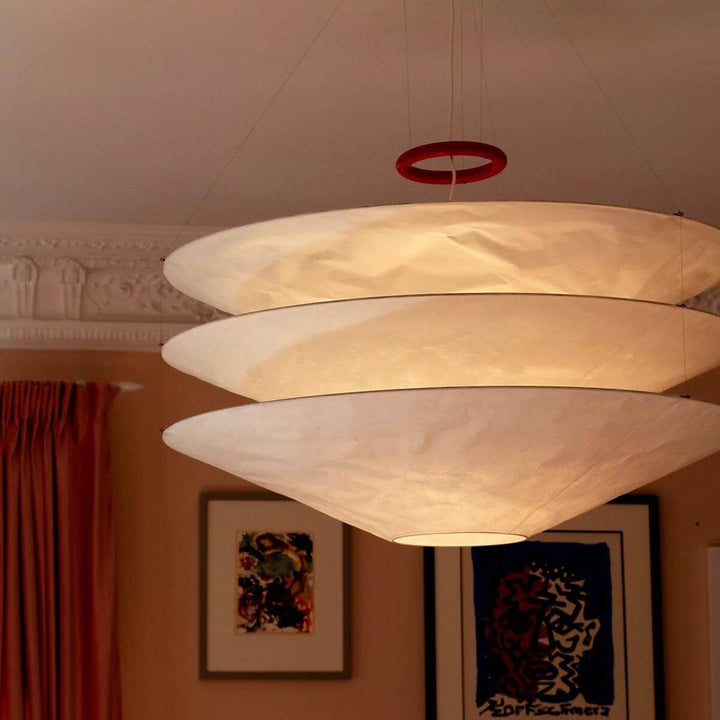 Large close-up of a glowing layered white pendant shade in a warm room.
