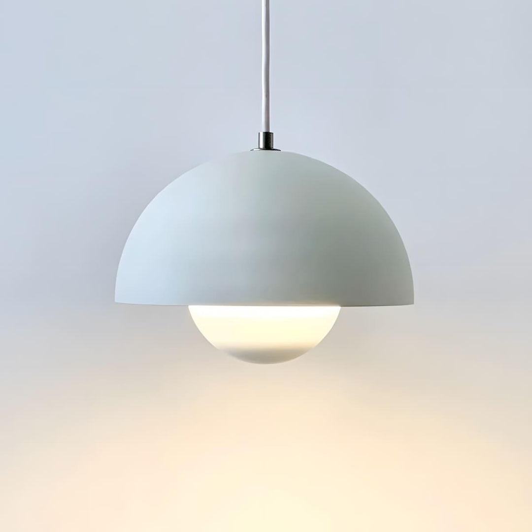 Matte white Flowerpot pendant lamp shown lit against a wall.