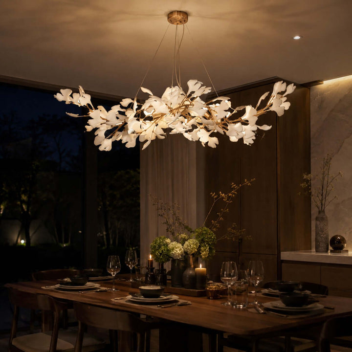 Ceramic leaf chandelier glowing above a dining table in a dark evening room.