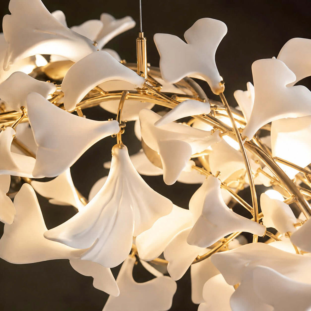 Close-up of white ceramic ginkgo leaves on a rose gold chandelier frame.