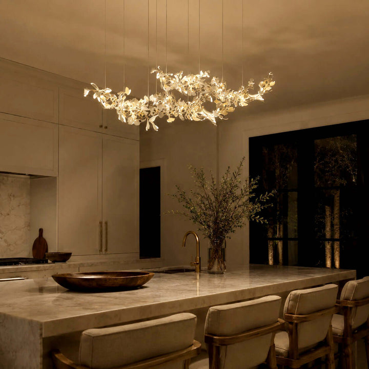 Gingko ceramic leaf chandelier glowing above a kitchen island at night.