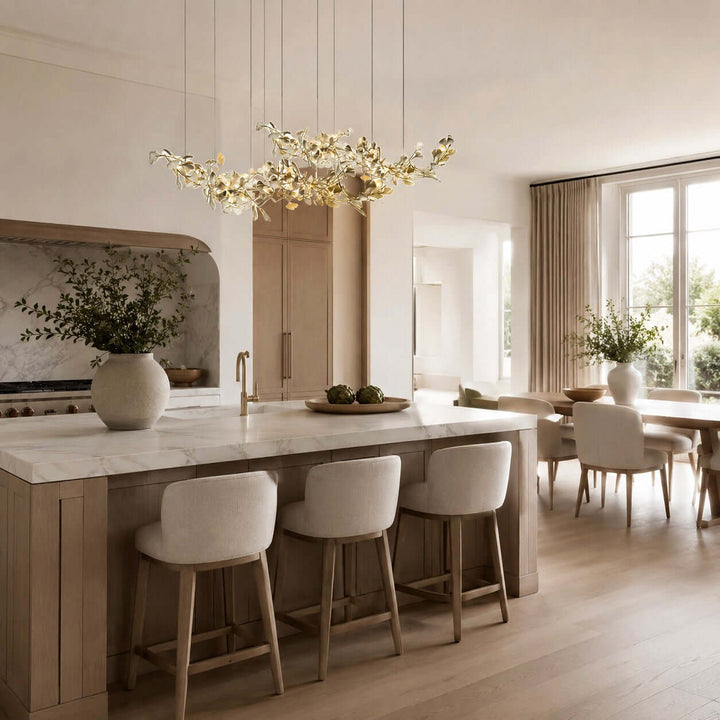White ceramic leaf chandelier hanging over a kitchen island with stools.