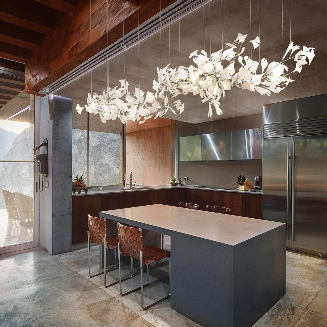 Gingko chandelier with ceramic leaves above a marble kitchen island.