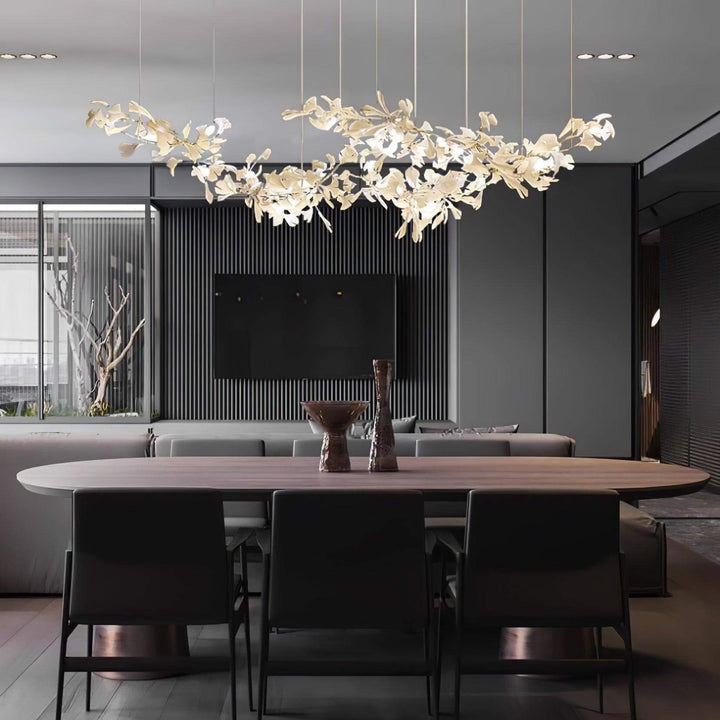 Gingko linear chandelier above a modern dining table beside a kitchen.